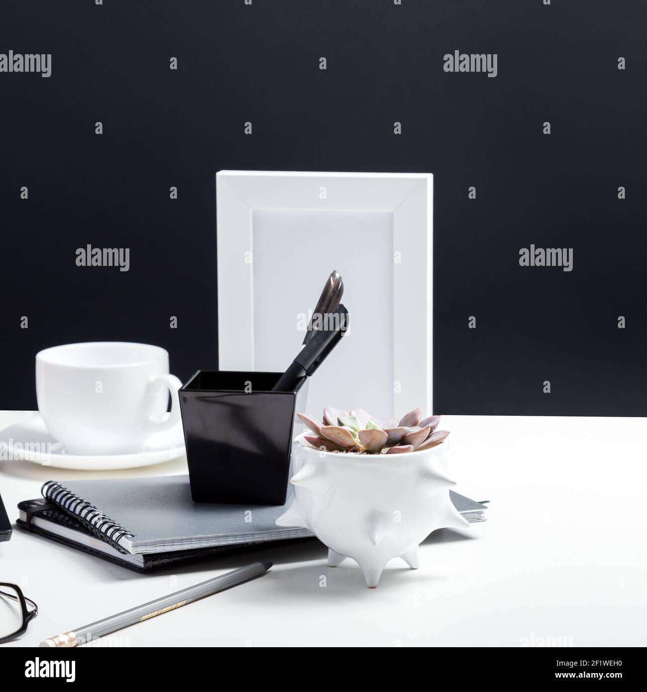 Forniture per ufficio su ambienti di lavoro minimalistici in bianco e nero con forniture per ufficio, taccuini, fiori di piante per ufficio su tavolo per lavoro o studio. Ho Foto Stock