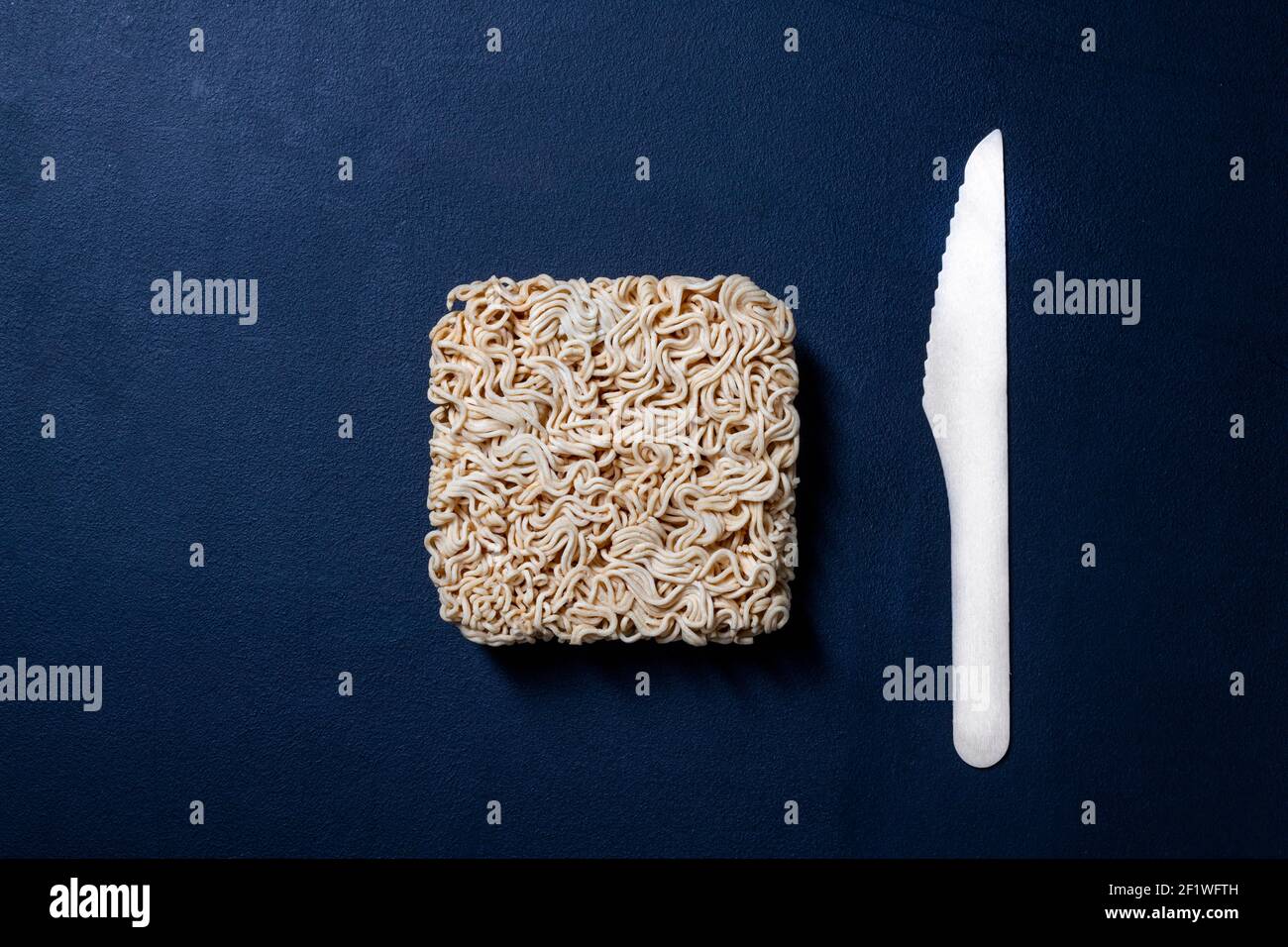 Zuppa cinese di noodle sul tavolo da cucina. Posate monouso in legno per mangiare pasti istantanei. Sfondo scuro. Foto Stock