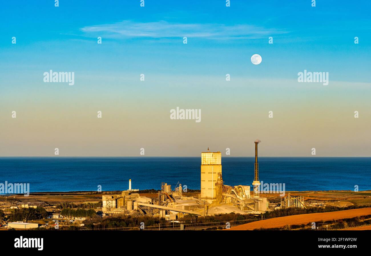 Luna piena di neve che si erge sulle opere di cemento di Dunbar, faro di Barns Ness e impianto di recupero di energia di Viridor, East Lothian, Scozia, Regno Unito Foto Stock