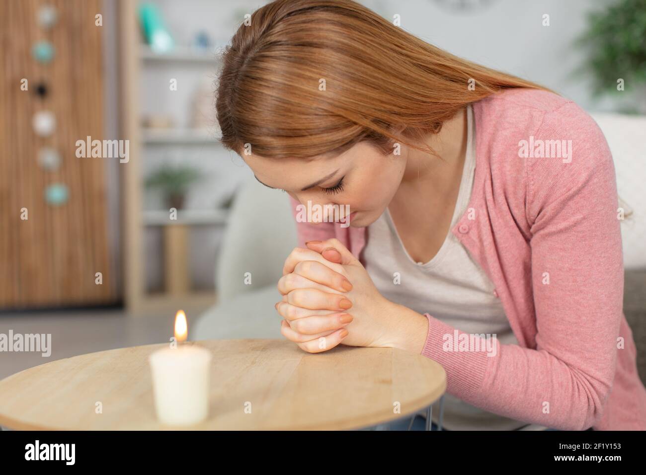 donna che prega depressa a casa Foto Stock