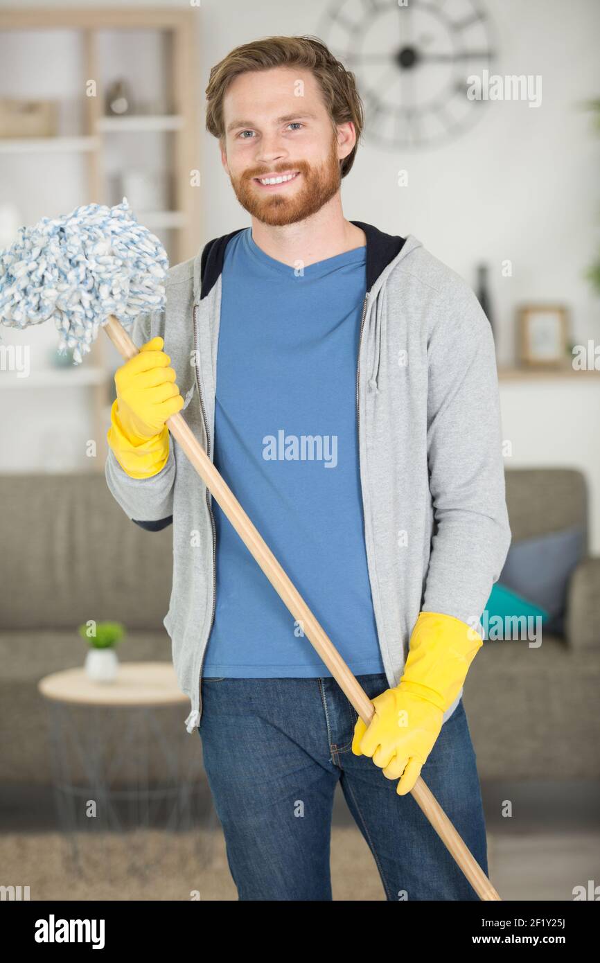 ritratto di giovane uomo che tiene un mop pavimento Foto Stock