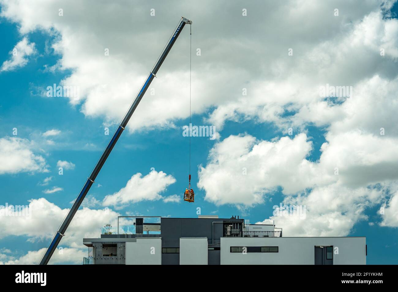 Brisbane, Australia - lavoratori edili sollevati in gabbia da una gru Foto Stock