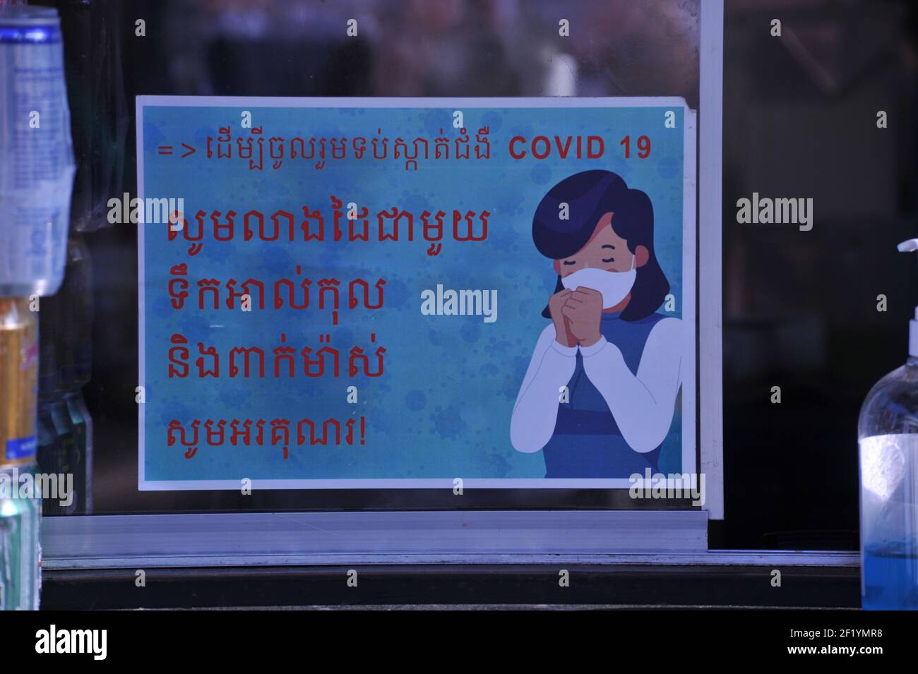 Durante un'epidemia di COVID - 19, un segno in Khmer script che avverte le persone di indossare maschere facciali al mercato di Kandal durante la pandemia del coronavirus. Phnom Penh, Cambogia. © Kraig Lieb Foto Stock