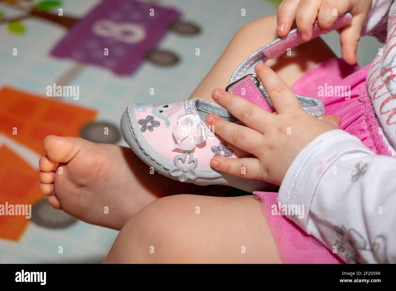 Una bambina di un anno sta giocando con le scarpe. Immagine ravvicinata  delle mani e dei piedi Foto stock - Alamy