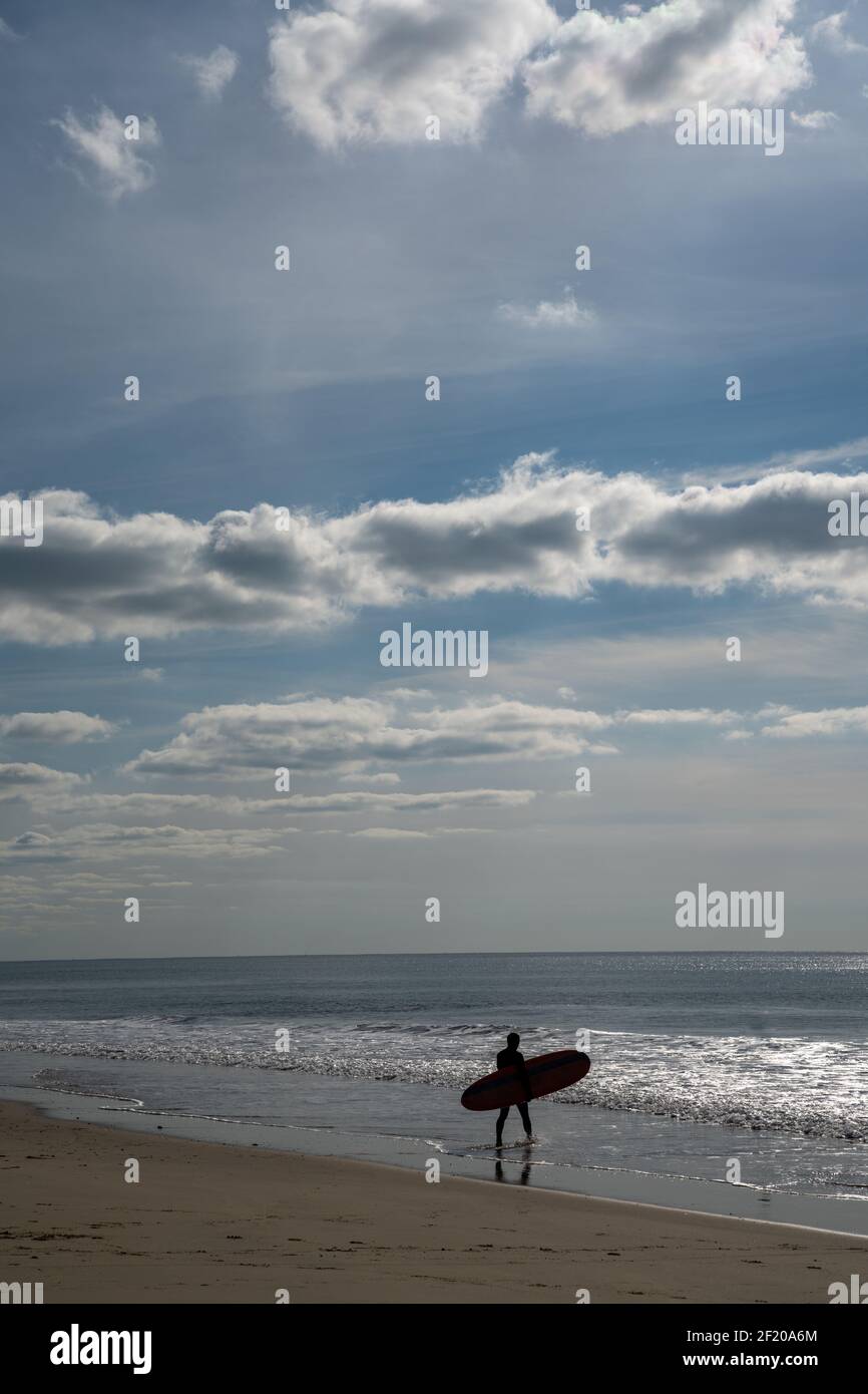 Un surfista maschile entra nell'oceano Atlantico sul Francese Cote d'Argent a prendere alcune onde Foto Stock