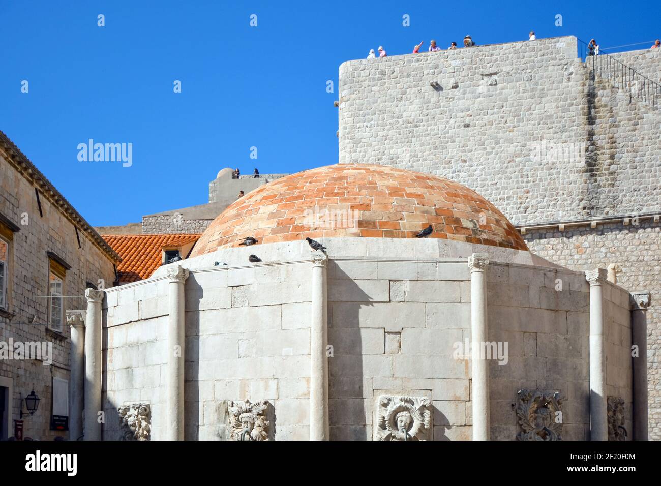 I turisti godono di una vista della grande Fontana di Onofrio dalle mura che circondano la città vecchia di Dubrovnik, Croazia Foto Stock