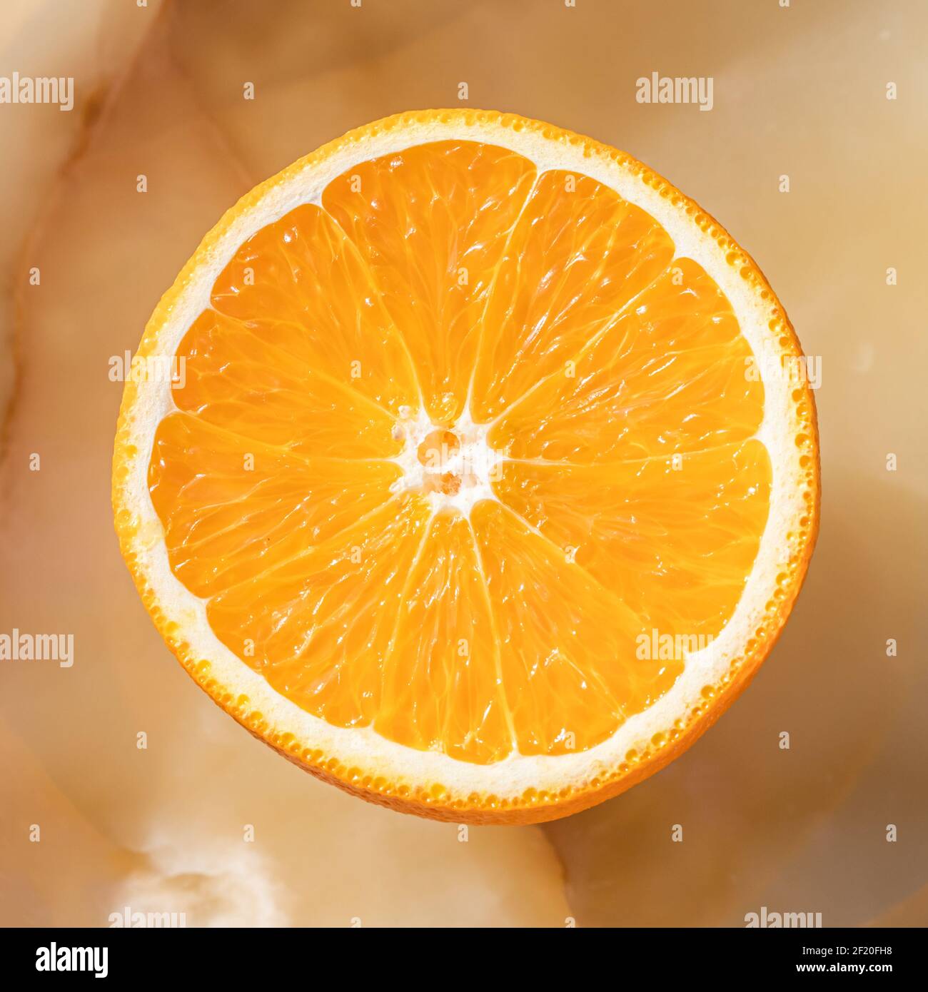 Metà di arancio su fondo in marmo onice. Frutta rotonda con percorso di ritaglio. Foto Stock