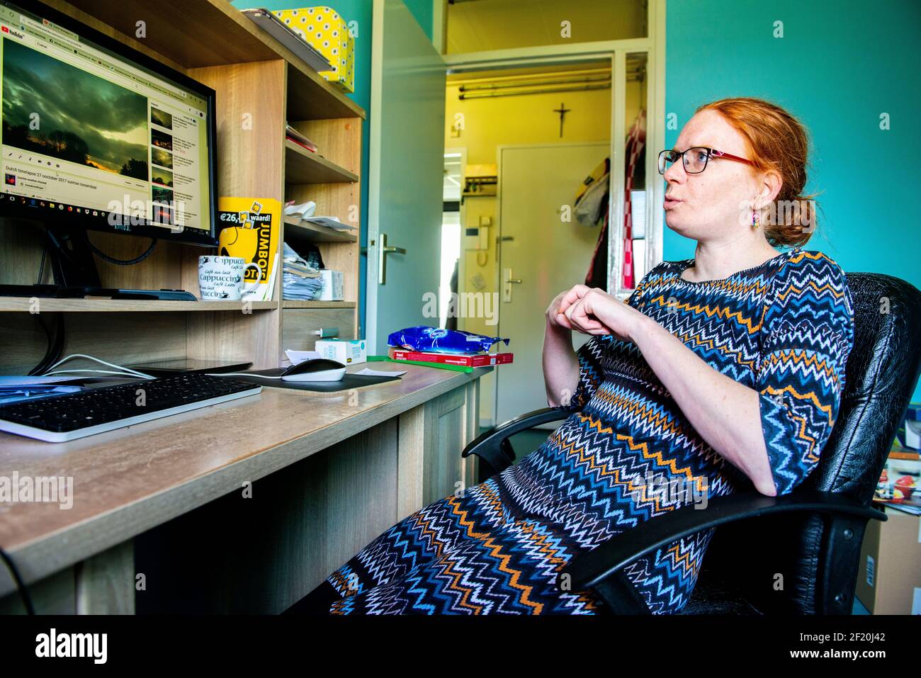 Roosendaal, Paesi Bassi. Giovane donna che lavora a casa, utilizzando il suo computer per caricare e gestire le sue foto sul sito Web del microstock Dreamstime. Foto Stock