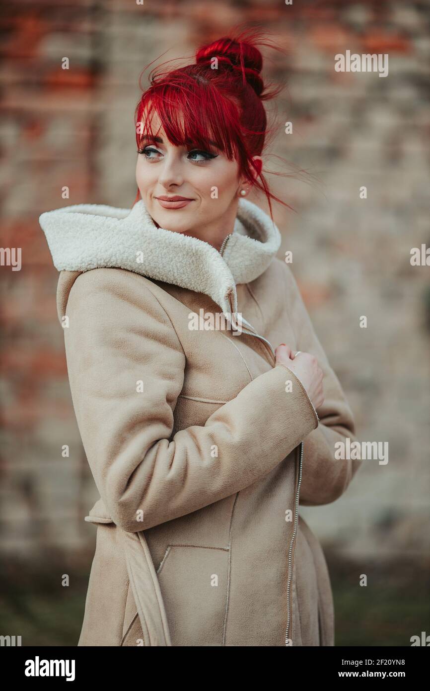 Giovane donna dai capelli rossi con bangs che indossa un caldo cappotto  invernale in uno sfondo sfocato Foto stock - Alamy