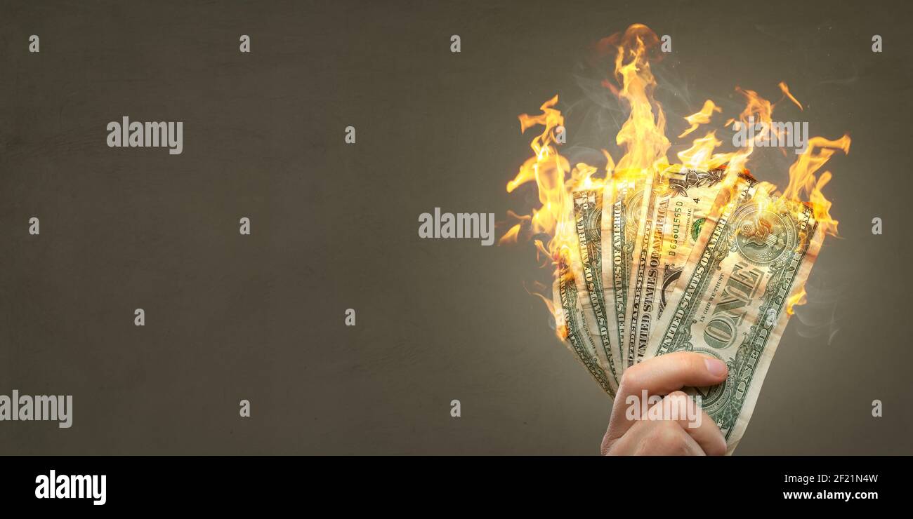 Bruciare le banconote in dollari tenute da una mano Foto Stock
