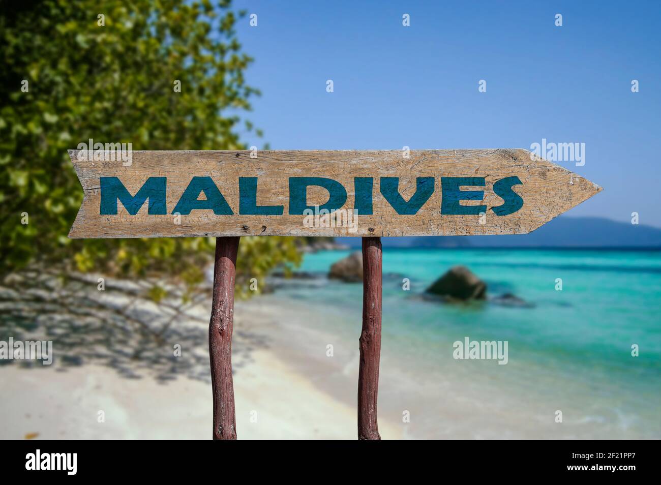 Maldive freccia di legno strada segno contro la spiaggia tropicale con sabbia bianca e sfondo di acqua turchese. Viaggio alle Maldive concetto. Foto Stock