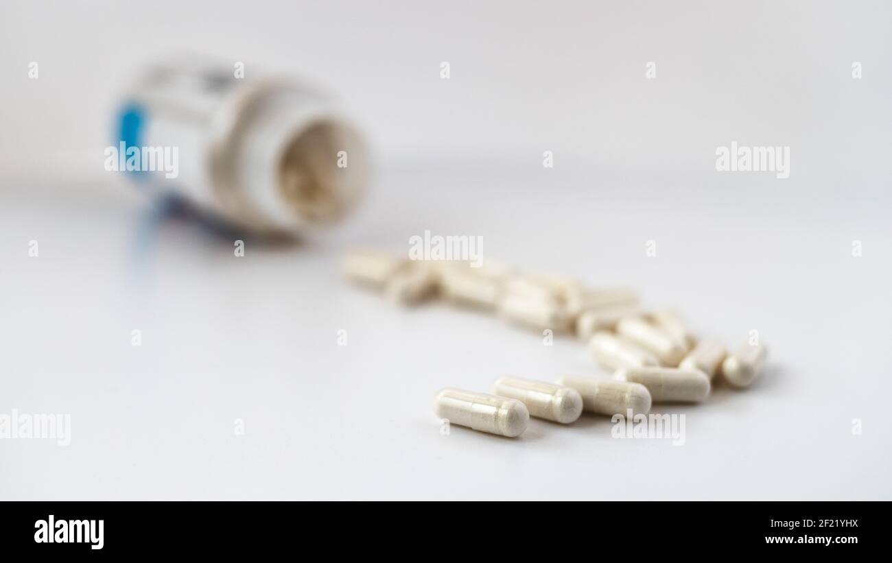 foto a fuoco selettivo delle capsule di orotato di litio, versata dal vaso. concetto dietetico. supplemento dietetico foto a profondità di campo limitata Foto Stock