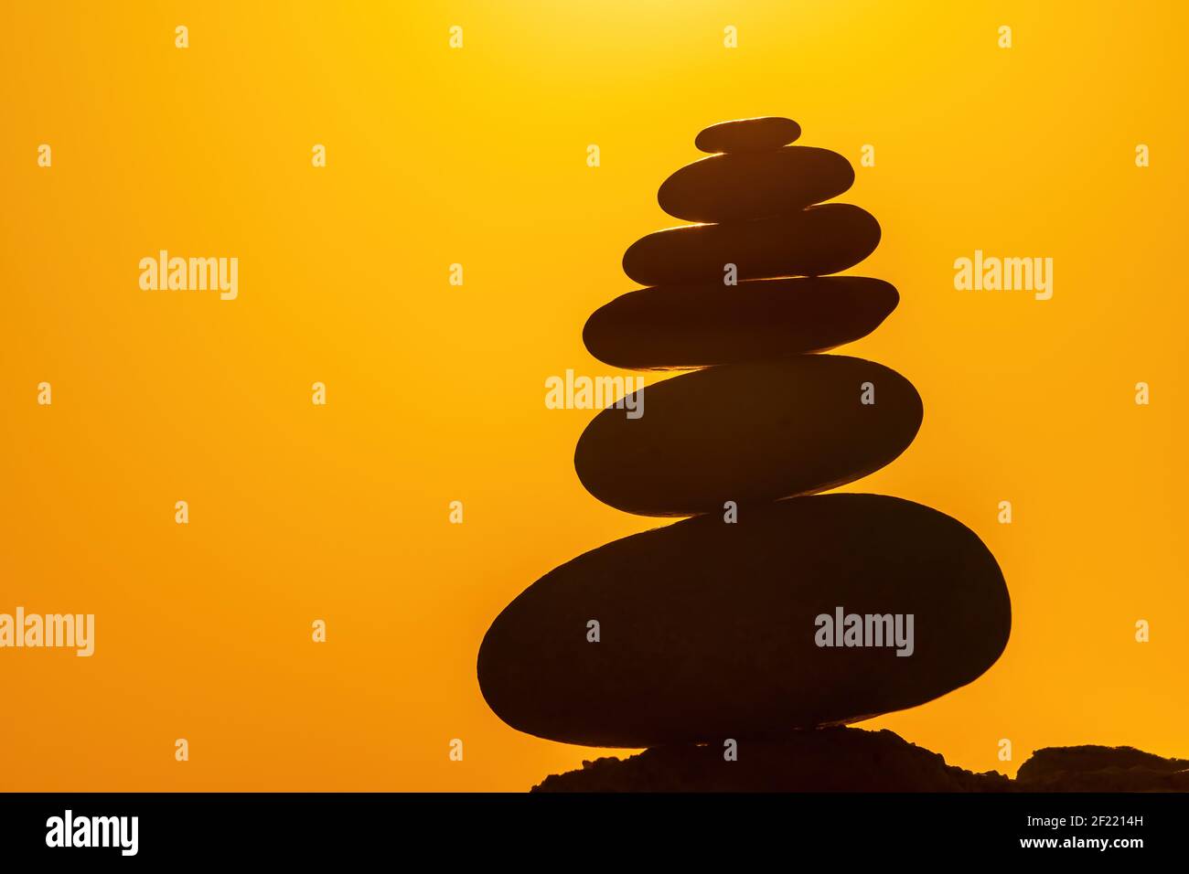 Profilo a piramide di ciottoli bilanciato sulla spiaggia. Astratto caldo tramonto bokeh con Mare sullo sfondo. Pietre Zen sulla spiaggia di mare, meditazione, spa Foto Stock