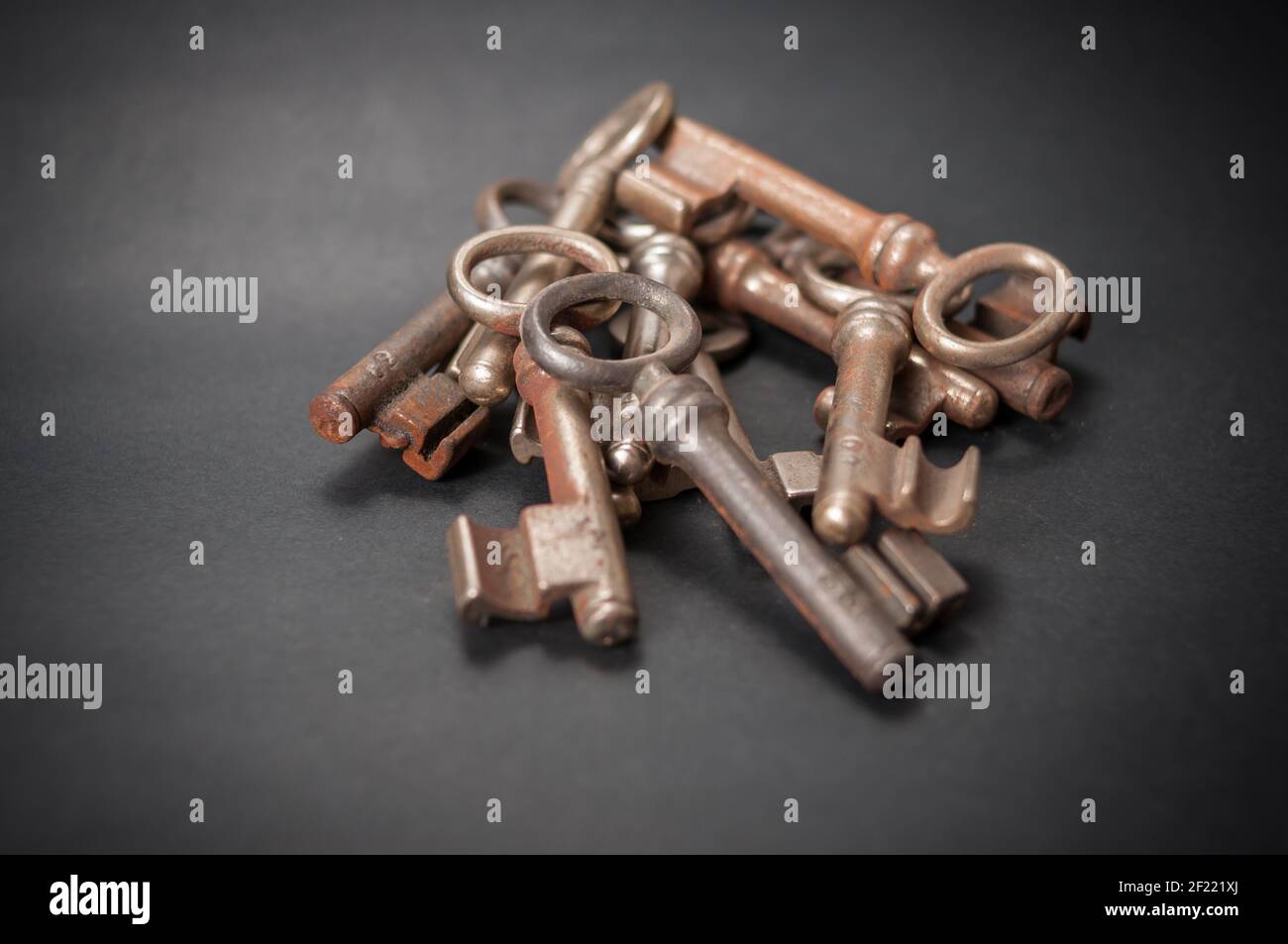 Accatastati le vecchie chiavi del tumbler sono arrugginite in differenti modi e giacere su uno sfondo nero Foto Stock