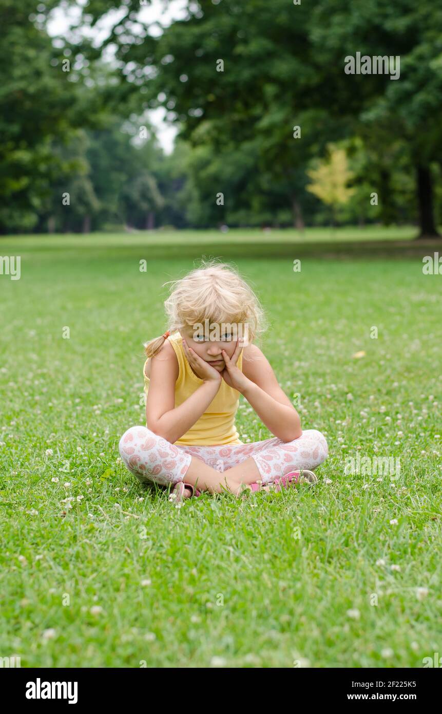 Bella ragazza bionda seduta sul prato Foto Stock