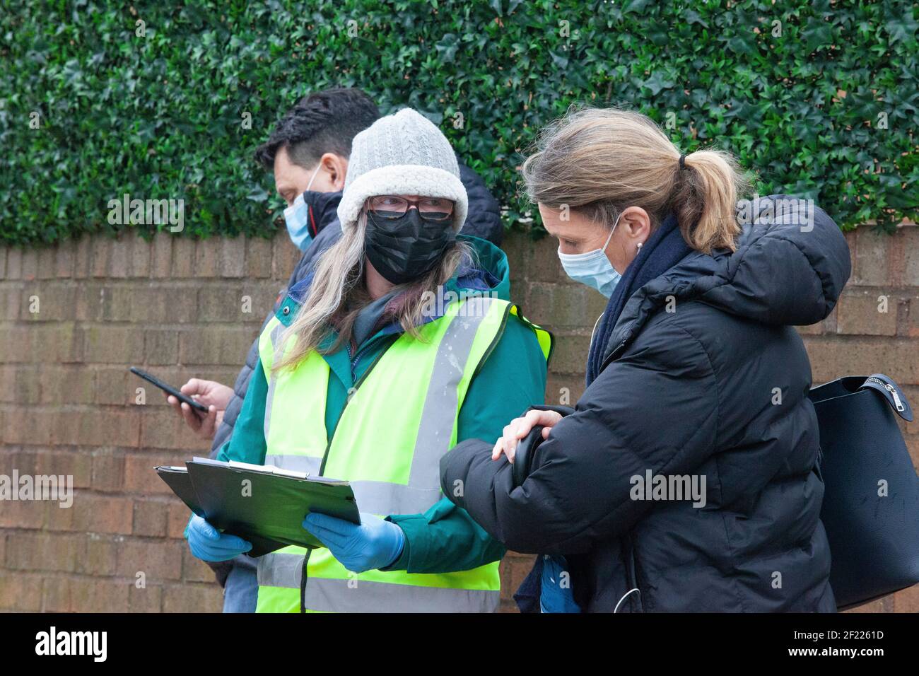 Londra, Regno Unito, 10 marzo 2021: Le persone attendono le vaccinazioni al di fuori di un centro NHS a Balham, a sud di Londra. I volontari sono stati cruciali nell'assistere il personale di NHS nel lancio di vaccino molto riuscito, che ha dato quasi 23 milione di persone le loro prime gib -- più di un terzo della popolazione. Anna Watson/Alamy Live News Foto Stock