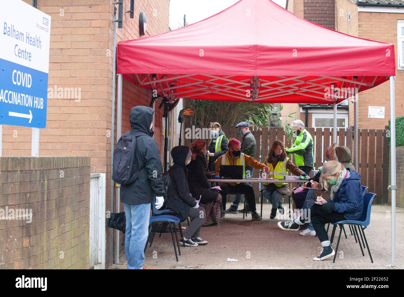 Londra, Regno Unito, 10 marzo 2021: Le persone attendono le vaccinazioni al di fuori di un centro NHS a Balham, a sud di Londra. I volontari sono stati cruciali nell'assistere il personale di NHS nel lancio di vaccino molto riuscito, che ha dato quasi 23 milione di persone le loro prime gib -- più di un terzo della popolazione. Anna Watson/Alamy Live News Foto Stock