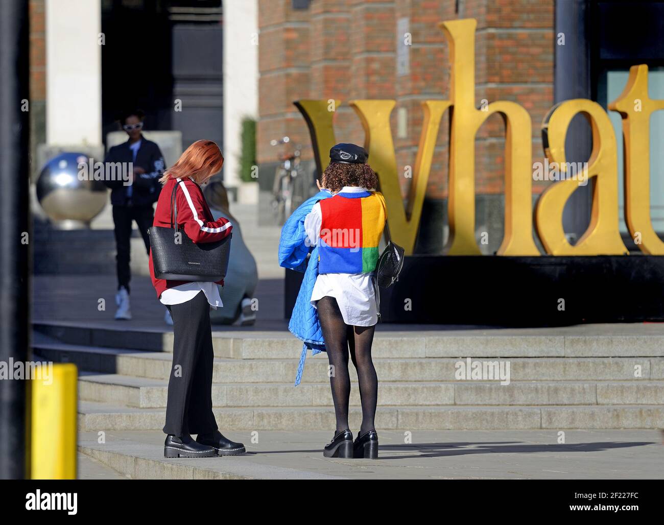 Londra, Inghilterra, Regno Unito. Giovane donna dai vestiti luminosi che fotografa un'installazione d'arte vicino alla Cattedrale di San Paolo Foto Stock