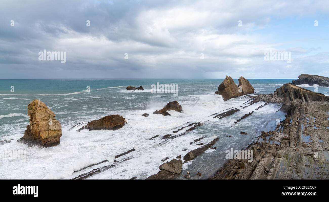 Costa rocciosa e selvaggia con onde tempestose che colpiscono la riva Foto Stock