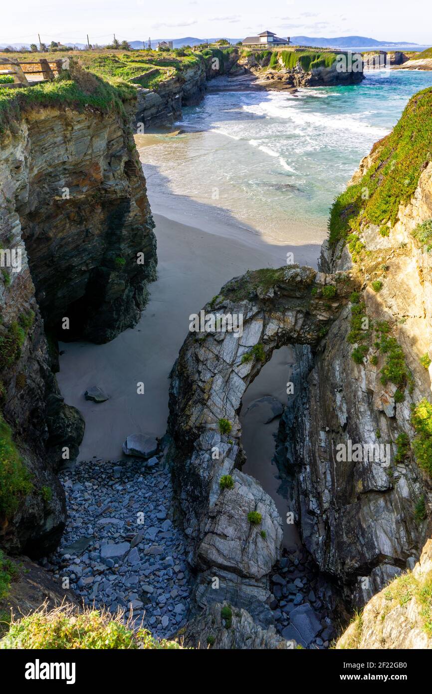 Calda serata d'oro su una spiaggia di sabbia con jagged e. scogliere frastagliate Foto Stock