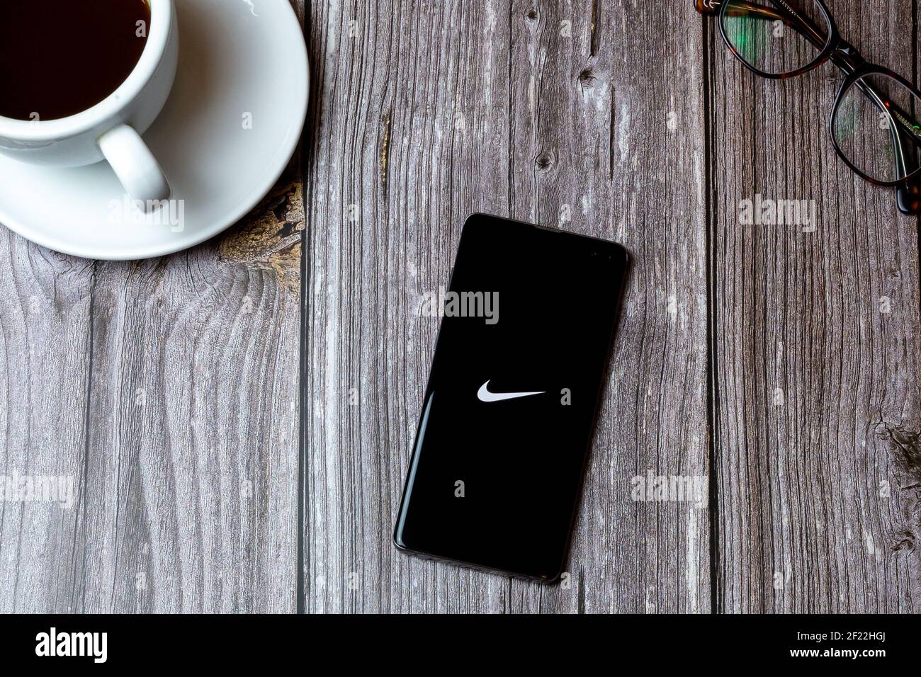 Un telefono cellulare o un telefono cellulare posato su un legno Tavolo con l'app Nike shopping aperta sullo schermo ad un caffè Foto Stock