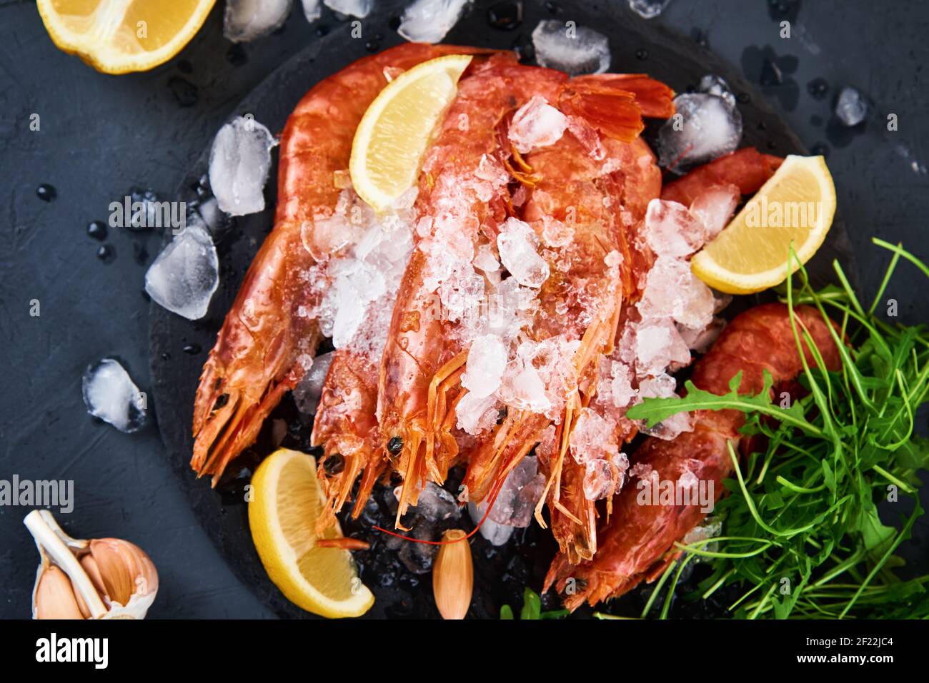 Pesce surgelato. Gamberetti freschi con limone su fondo scuro. Gamberi rossi crudi Foto Stock