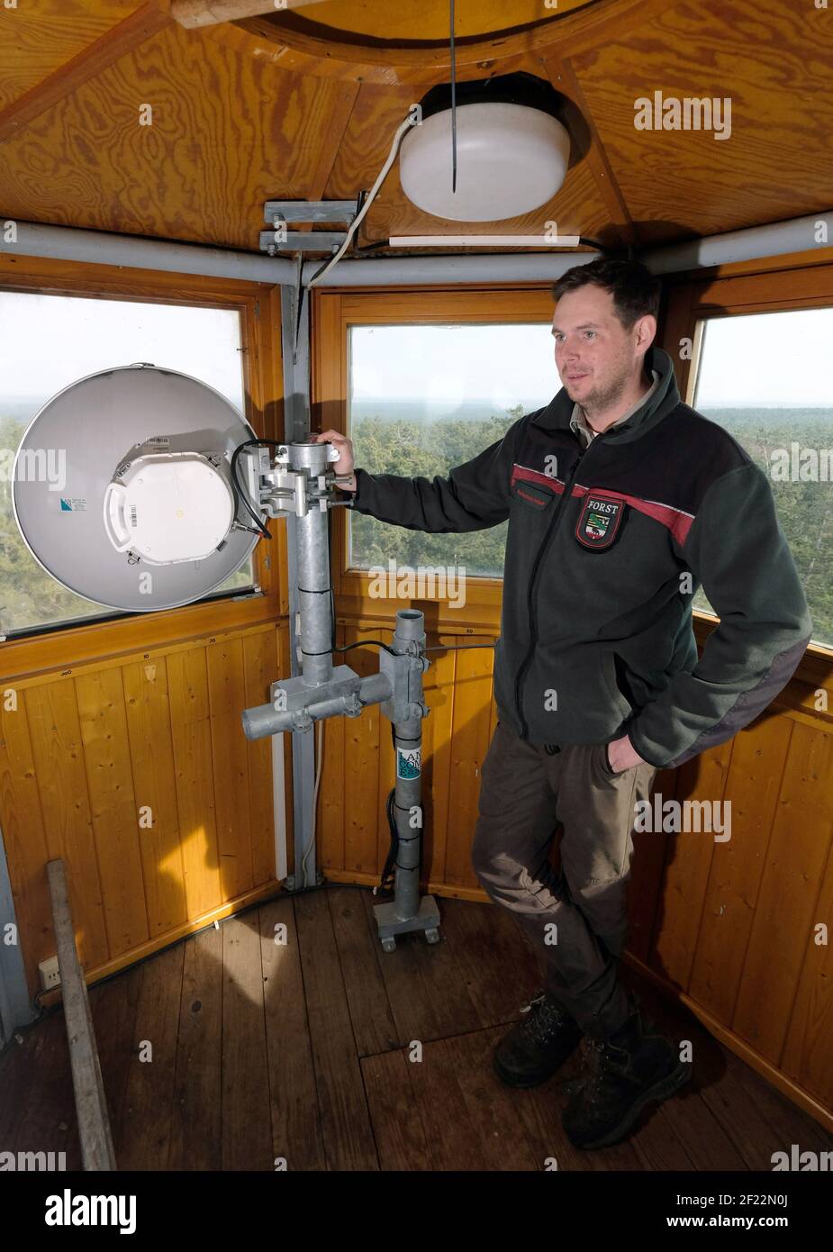 Arnsdorf, Germania. 10 marzo 2021. Philipp Nahrstedt, capo dell'ufficio forestale dell'area di Annaburg, si trova all'interno di una torre di avvistamento incendi presso le antenne radio direzionali a Glücksburger Heide. In Sassonia-Anhalt, 1.2 milioni di euro sono stati investiti nel sistema di allarme rapido incendi boschivi "Fire Watch". Lo stato si basa sulla tecnologia derivata dalla tecnologia aerospaziale per il rilevamento precoce degli incendi boschivi; i sensori ottici sono stati installati su torri di avvistamento incendi, montanti per telefoni cellulari e edifici alti. Credit: Sebastian Willnow/dpa-Zentralbild/dpa/Alamy Live News Foto Stock