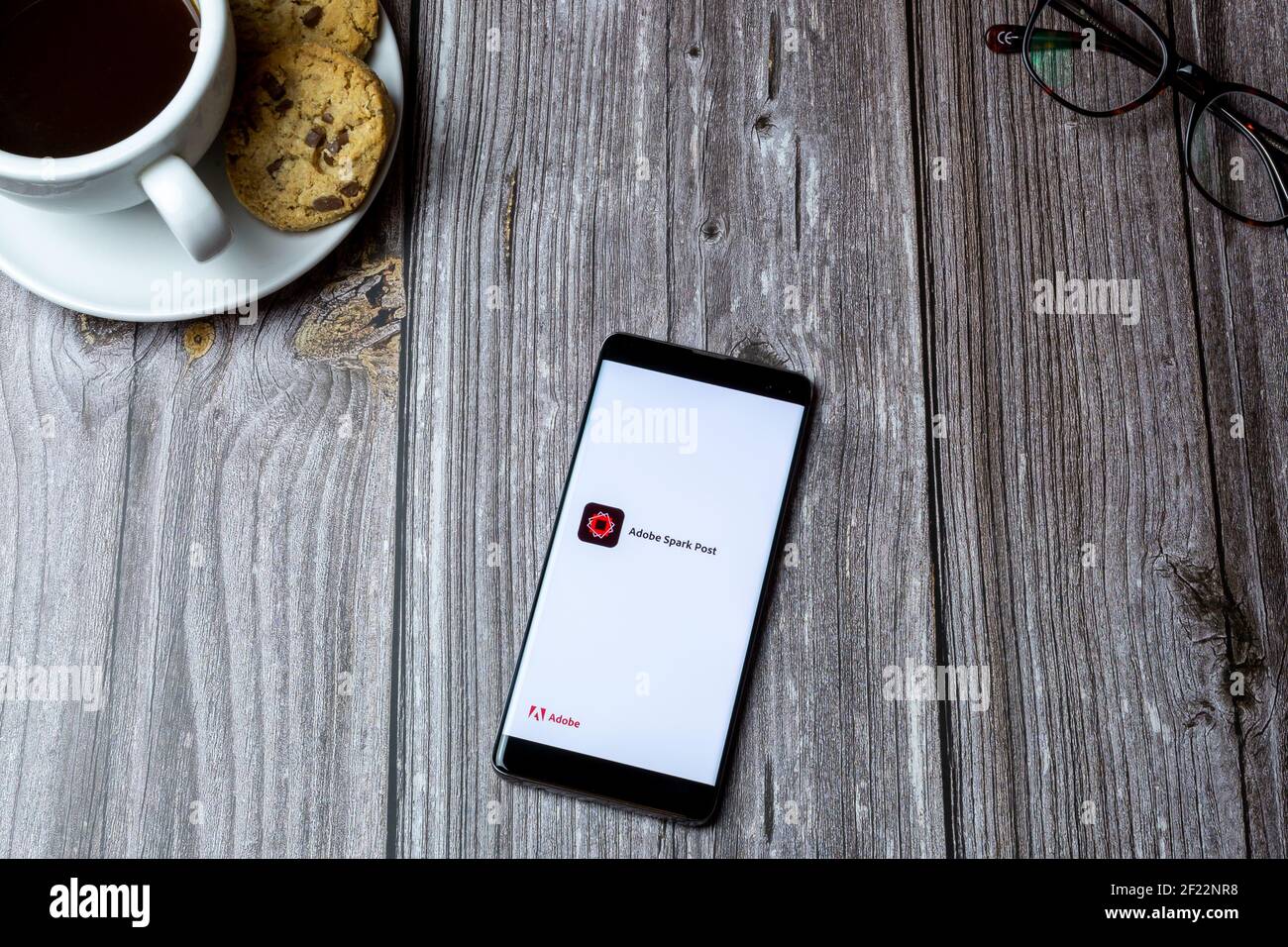 Un telefono cellulare o un telefono cellulare posato su un legno tabella con l'app adobe spark aperta sullo schermo Foto Stock