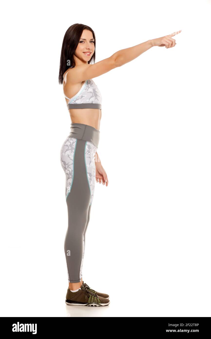 Profilo o giovane donna piuttosto muscolare che posa su sfondo bianco puntando sullo spazio vuoto Foto Stock