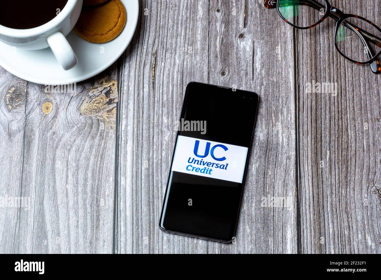 Un telefono cellulare o un telefono cellulare posato su un legno Tavolo con l'app di credito universale aperta sullo schermo Foto Stock