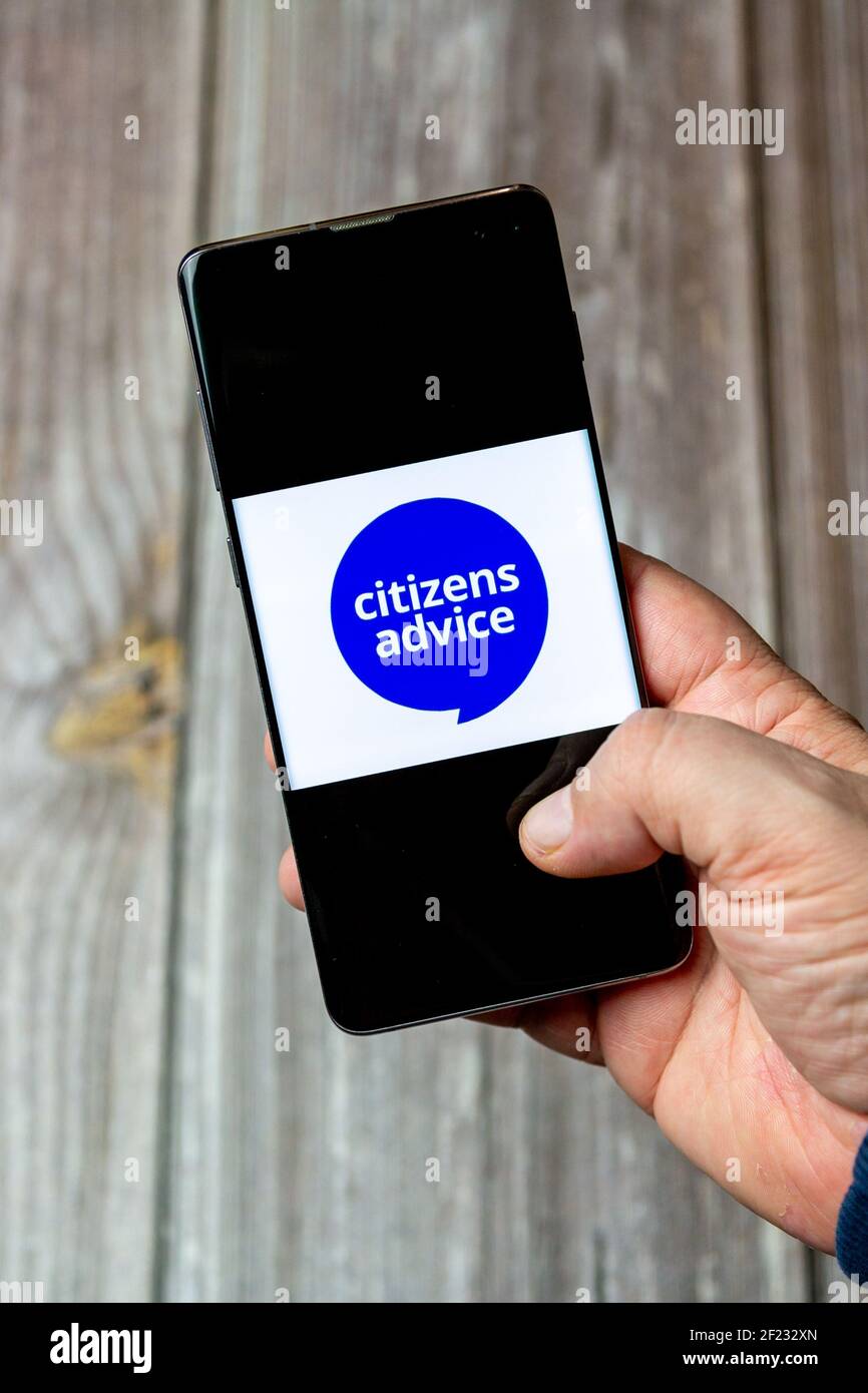 Un telefono cellulare o un telefono cellulare in attesa in un Mano con il logo Citizens Advice Bureau aperto sullo schermo Foto Stock