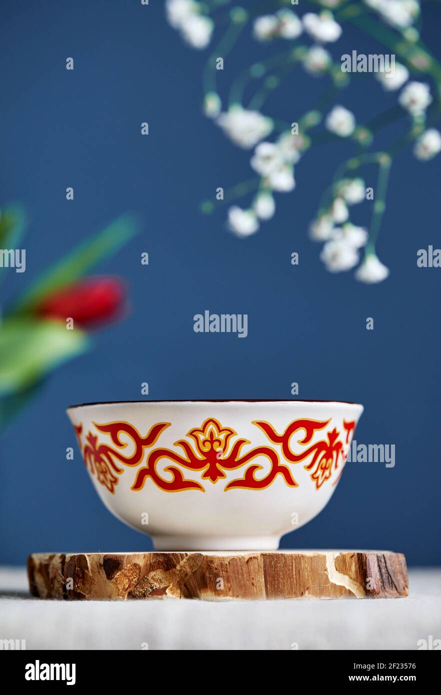 Kese tradizionale del tè kazako con tè nero e latte all'interno vicino fiori su sfondo blu durante il festival di Nauryz. Foto Stock