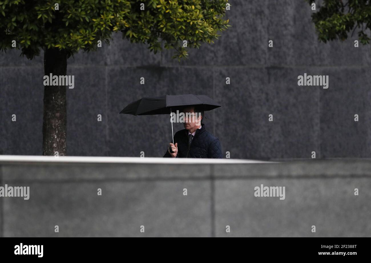 Un uomo usa un ombrello al Convention Center di Dublino durante un periodo di maltempo, come Met Eireann ha emesso un avviso di stato giallo vento per l'intero paese. Data immagine: Mercoledì 10 marzo 2021. Foto Stock