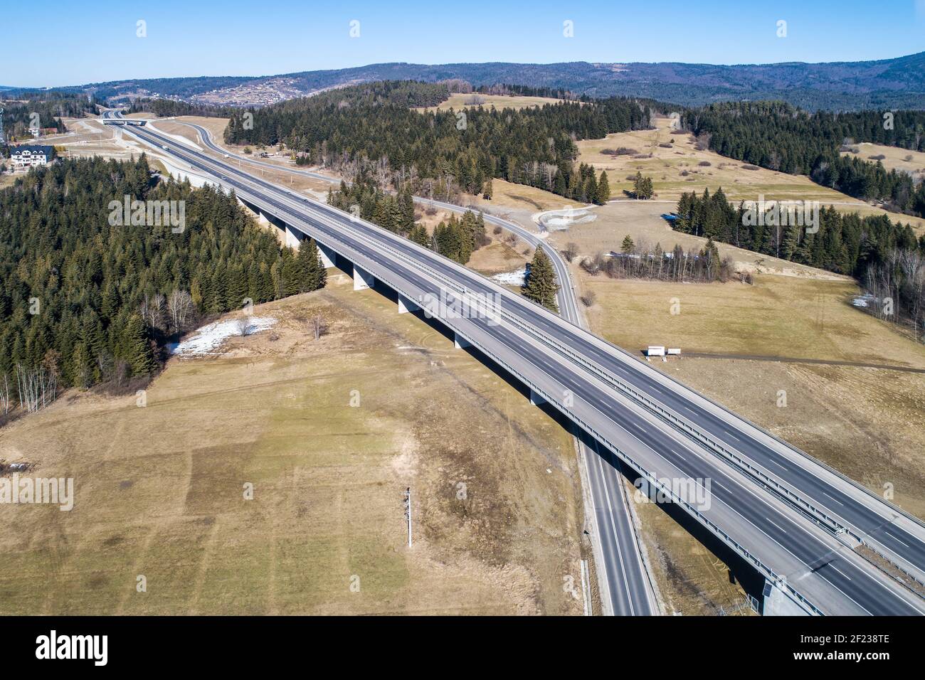 Vecchia strada e nuova autostrada da Cracovia a Zakopane in Polonia, chiamata Zakopianka con viadotti, crocevia elevato e auto. Vista aerea in inverno Foto Stock