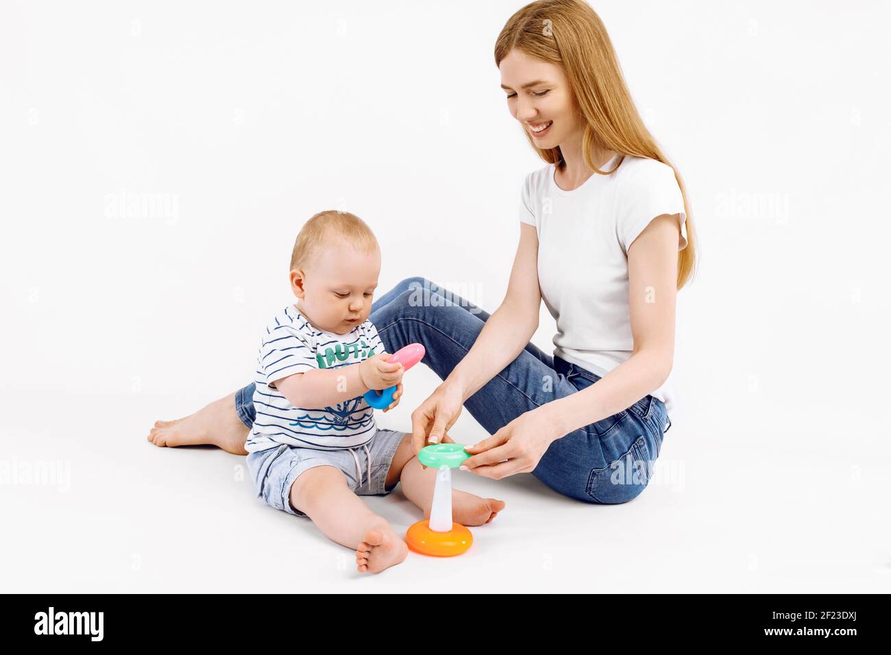 La mamma e il suo bambino giocano con il colorato giocattolo piramidale dell'arcobaleno, su uno sfondo bianco isolato, Giocattoli per bambini piccoli, Bambino con giocattoli educativi, precoce Foto Stock