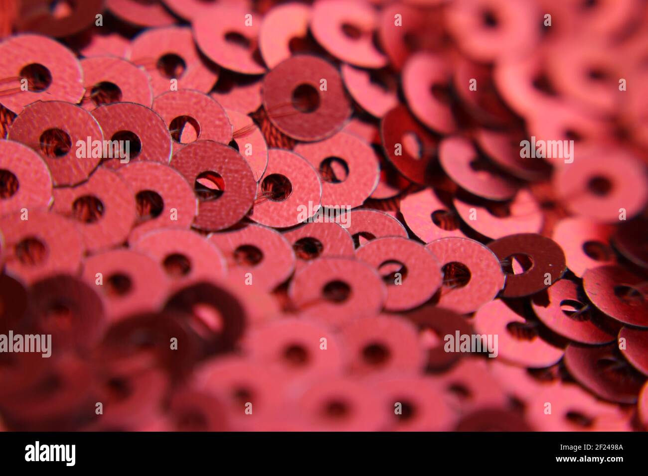Sfondo astratto, tessuto con applicazioni di molti payettes con il colore rosso scuro. Foto Stock