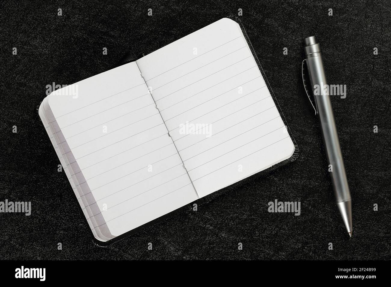aprire e lasciare vuoto il libro dell'agenda con la penna sulla superficie nera Foto Stock