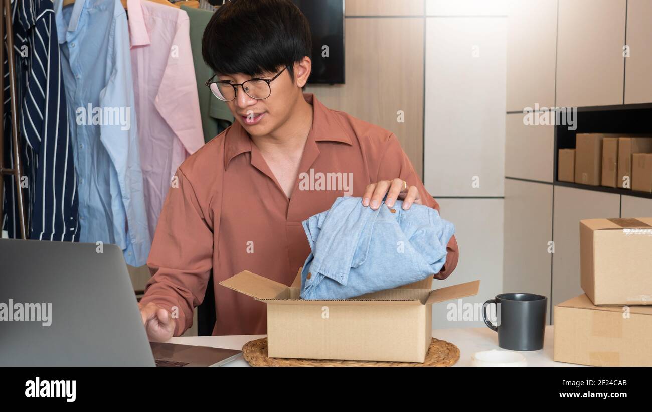 Il proprietario asiatico di affari che lavora a casa con la scatola di imballaggio del suo deposito in linea prepara per trasportare i prodotti ai clienti, lo stile di vita di generazione dell'alfa concep Foto Stock