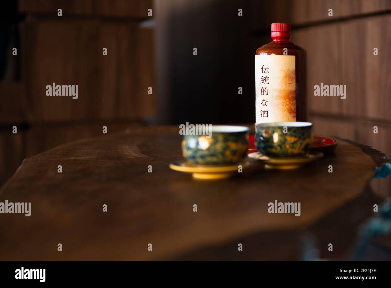 Due tazze orientali con una bottiglia di bevanda alcolica lo sfondo Foto Stock