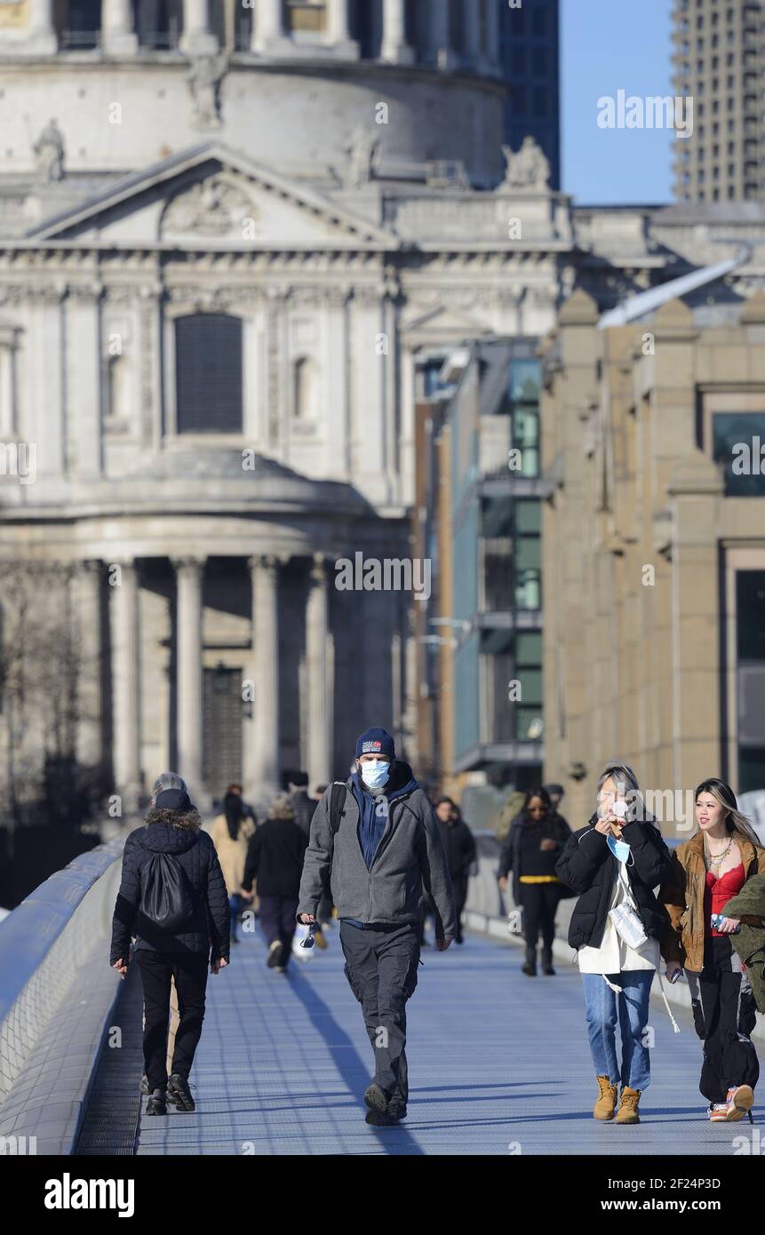 Londra, Inghilterra, Regno Unito. Persone che attraversano il Millennium Bridge indossando maschere per il viso durante la pandemia COVID, marzo 2021 Foto Stock