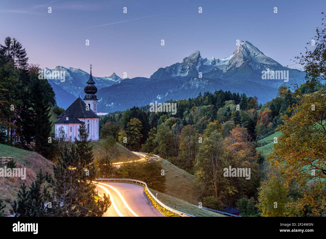 Sul monte Watzmann e la piccola Maria Gern chiesa all'alba con tracce di luce dai fari di automobile Foto Stock