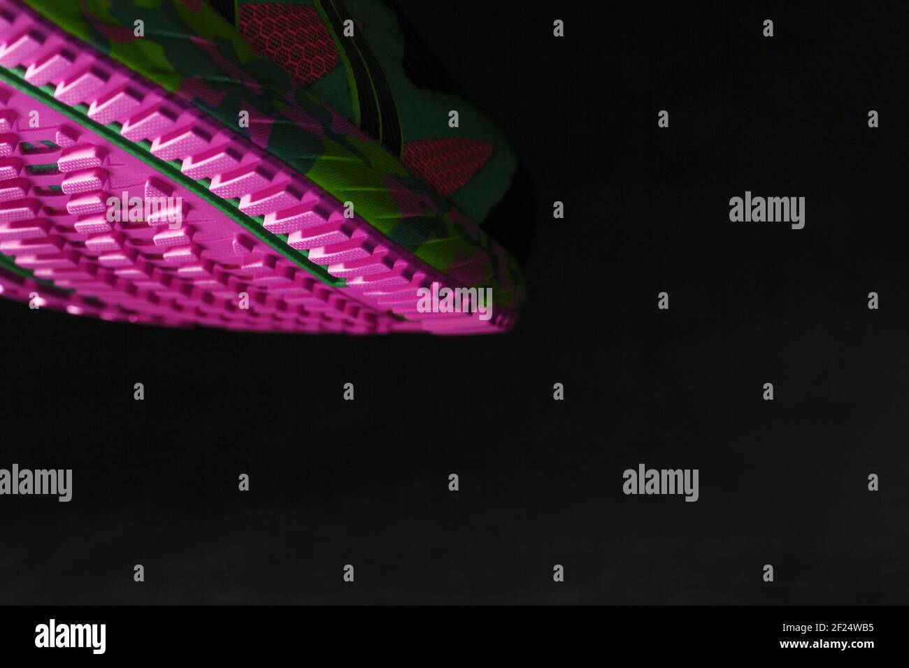 Suola rosa testurizzata di scarpe da running sportive su sfondo nero. Colori moderni pazzi. Stile sportivo, primo piano Foto Stock