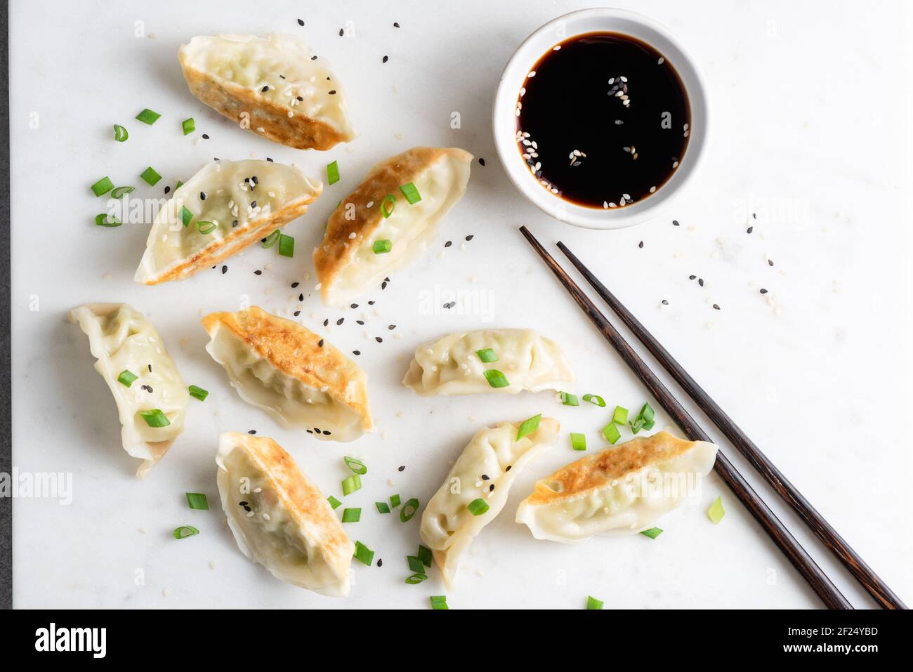 Gnocchi cinesi fritti di Gyoza serviti con scalioni, semi di sesamo e salsa di soia. Vista dall'alto. Cucina asiatica Foto Stock