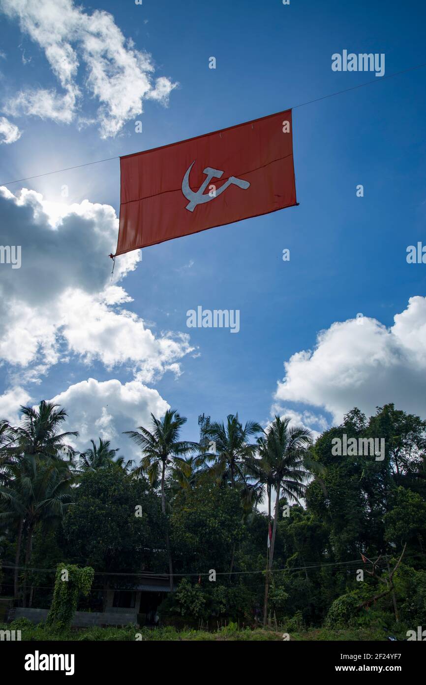 bandiera comunista. Martello e falce che rappresentano i contadini e gli operai, volando nel cielo blu denso nuvoloso. Foto Stock