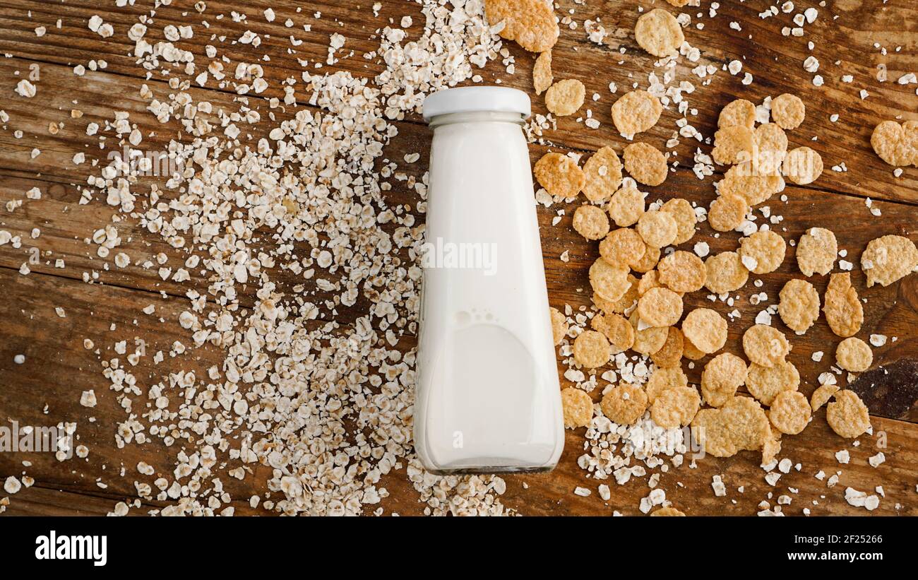 Bottiglia di latte fresco su fondo di legno con avena e cereali Foto Stock