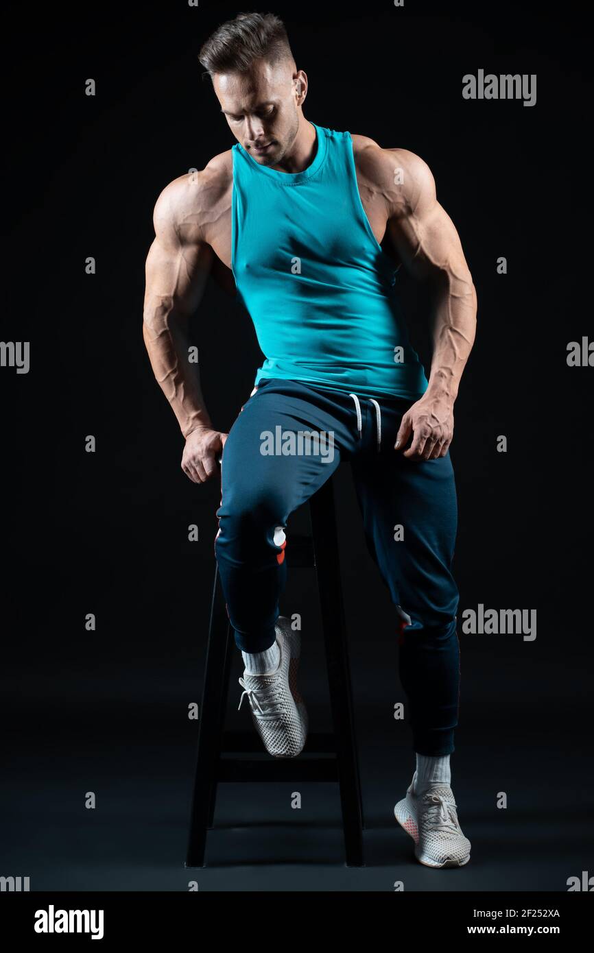 giovane bel bodybuilder uomo che posa in abbigliamento sportivo su sfondo  nero Foto stock - Alamy