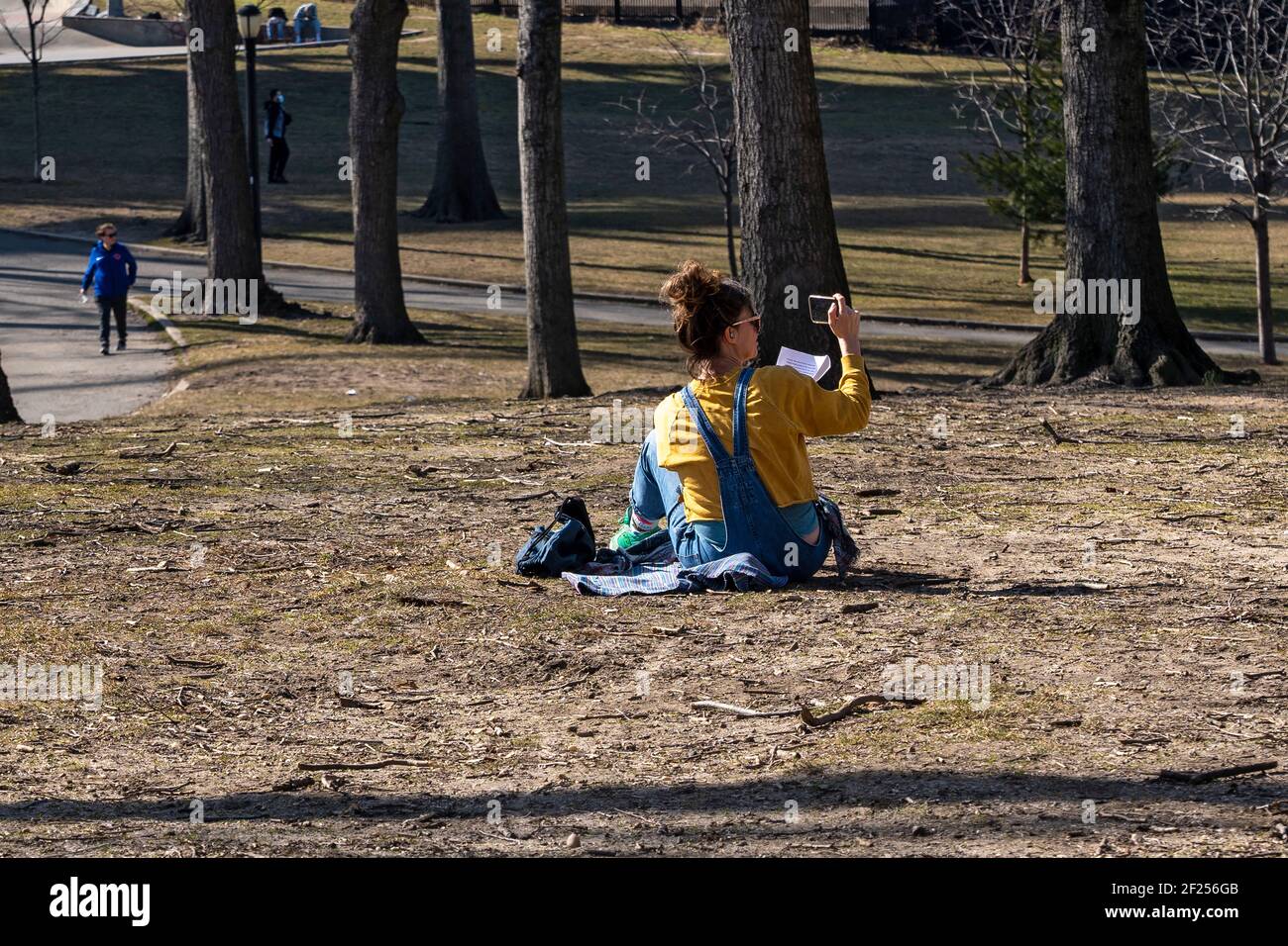 NEW YORK, NEW YORK - 9 MARZO: Una donna in videochiamata vista in un pomeriggio caldo ad Astoria Park il 9 marzo 2021 a New York City. Dopo giorni di neve Foto Stock