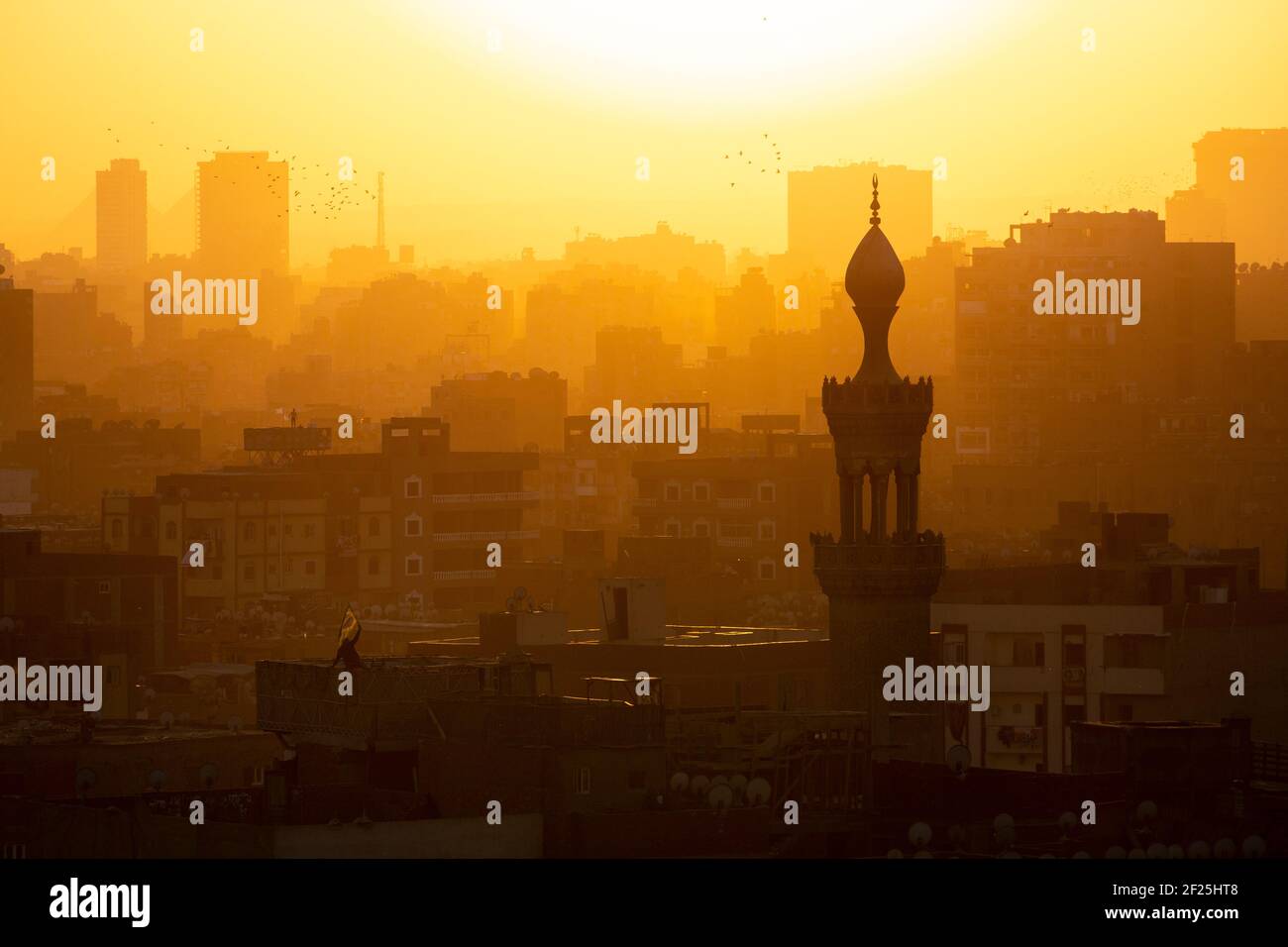 Il paesaggio urbano del Cairo al tramonto mostra l'uomo che svela la bandiera sulla terrazza sul tetto, come visto dal Parco al Azhar, Salah Salem St, El-DARB El-Ahmar, Cairo, Egitto Foto Stock