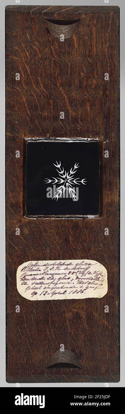 Sneeuwster.lastra di vetro quadrata con supporto in legno. Stella di neve in piano nero: Sei linee dal centro, con traversine a forma di lunare su cui i punti indicano. Foto Stock