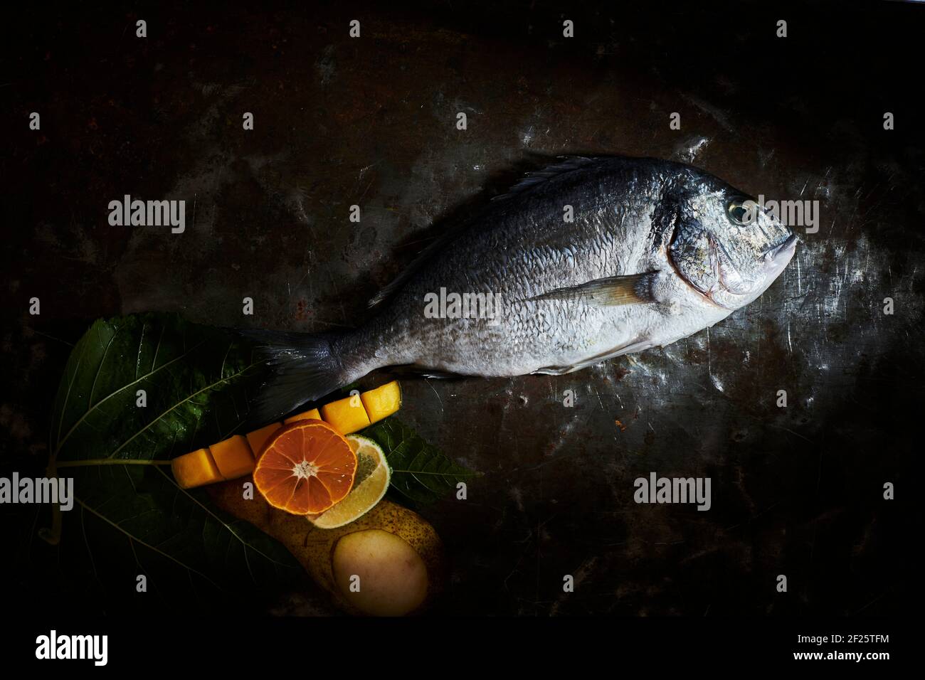 Non cotti dorate orate di testa su una piastra con i condimenti Foto Stock